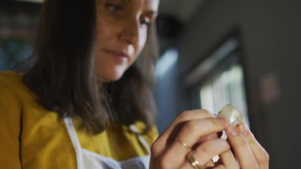 Close up of caucasian female jeweller carefully checking piece of jewelry