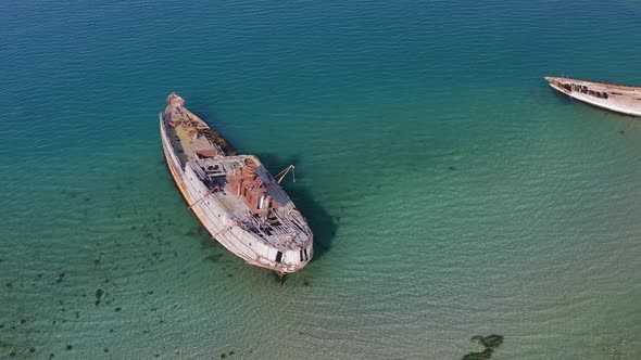 A Wrecked Wooden Ship Lies on the Seashore Covered with Rust