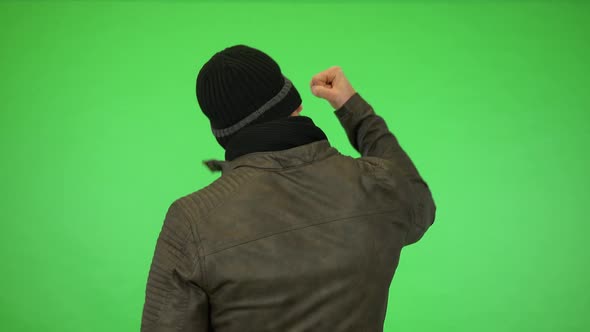 A Young Handsome Man in a Winter Outfit Cheers with His Back To the Camera - Green Screen Studio