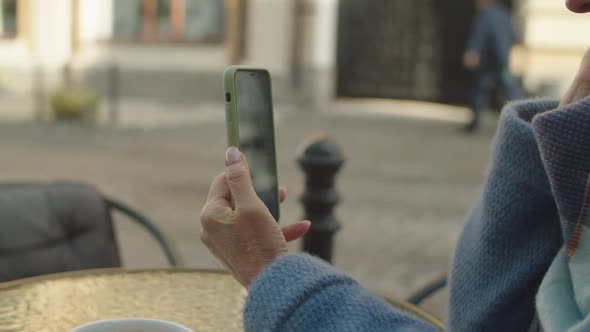 Elderly Woman Using Mobile Phone App for Online Video Call Outdoors