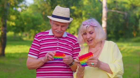 Stylish Senior Grandmother Grandfather Playing Squeezing Antistress Toy Simple Dimple Game in Park