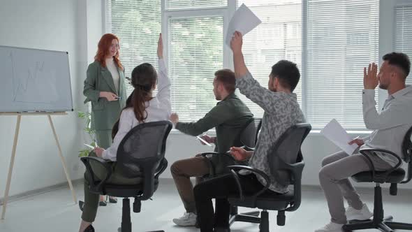 Young Business Woman Makes a Presentation of New Project on Flipchart for Female and Male Employees