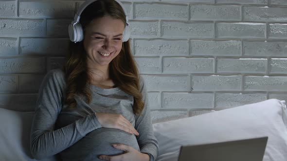 Pregnant Female in Headphones Laughing