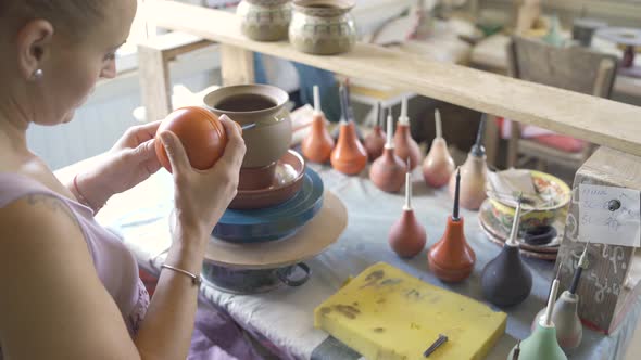 Female Potter Uses a Tool to Cover Clay Pot with Paint Working in Workshop