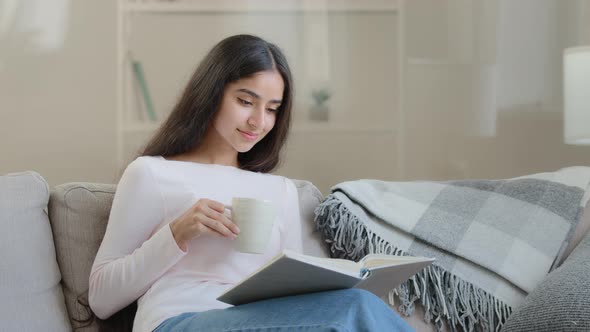 Serene Young Girl Student Daughter Relaxed Arabian Biracial Intelligent Woman Sits on Sofa Reads