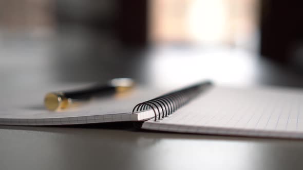 A black-gold pen lies on an open notebook 