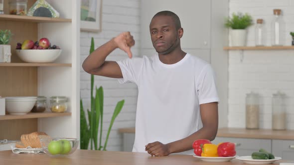 Sporty African Man Showing Thumbs Down While Standing in Kitchen