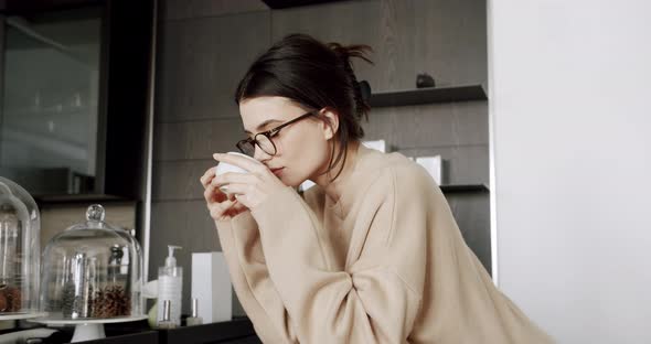 A Beautiful Young Woman is Drinking Tea Cup in the Modern Kitchen Room at Home