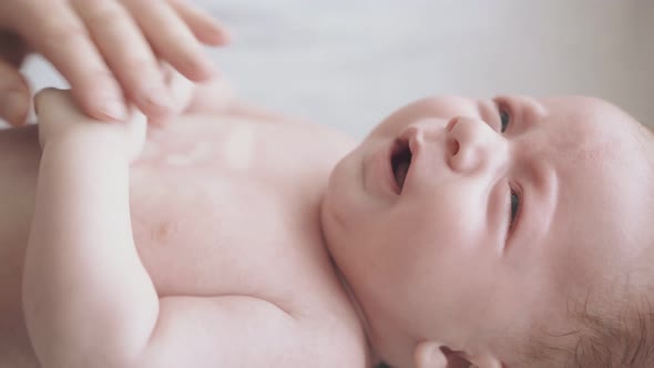 Infant Boy with Plump Cheeks Lies on Baby Changing Table