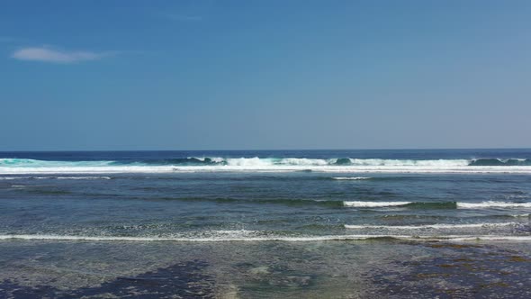 small ocean waves crash at low tide near Nyang Nyang beach in Uluwatu Bali