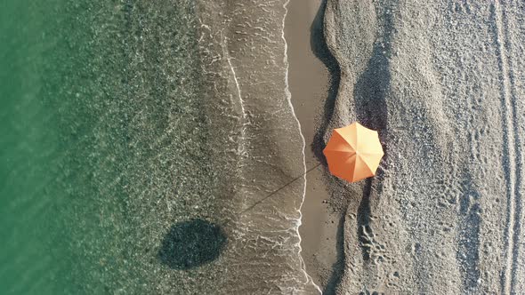 Orange Umbrella Near the Calm Waves of the Sea at Summer