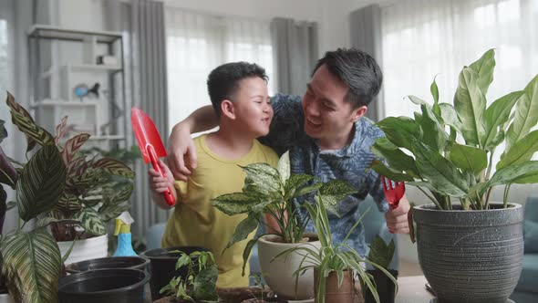 Asian Little Boy Kiss His Father While Taking Care Of Plant At Home