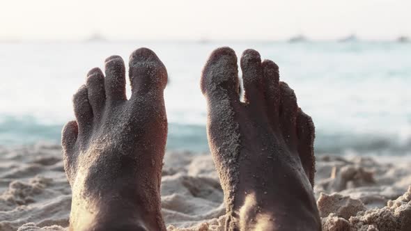 POV Feet of Young Man Lying on Sandy Beach By the Ocean During Sunset Zanzibar