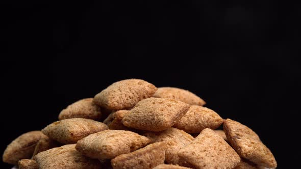 Crispy chocolate pads rotation in macro on black background. Cereal dessert for a fast breakfast