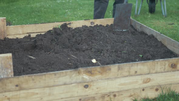 Leveling out soil in raised garden bed with shovel