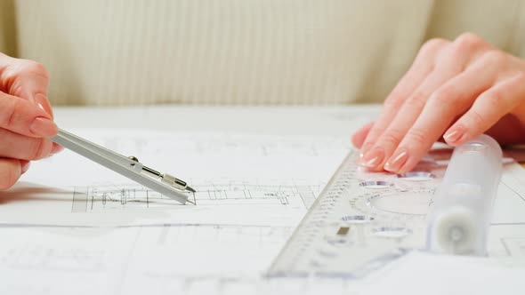 Architect Designer Using Compass to Draw Plan Blueprint Closeup