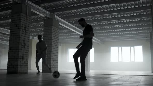 Two Guys Play with a Soccer Ball in the Parking Lot