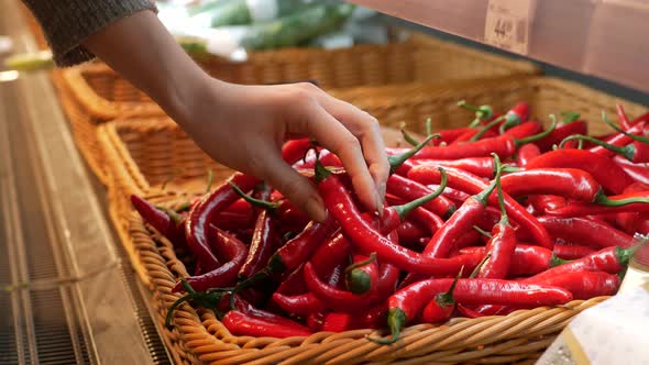 woman buying chili peppers at grocery store