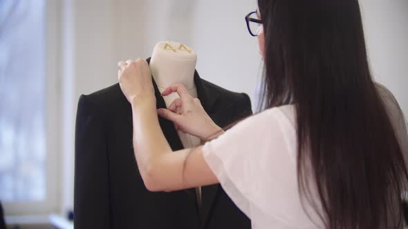 A Young Woman Cleans a Black Jacket on a Mannequin