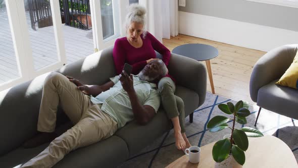 Mixed race senior couple using smartphone in the living room at home