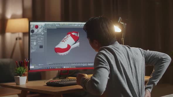 Asian Male Footwear Designer Having A Backache While Designing Shoe On A Desktop At Home