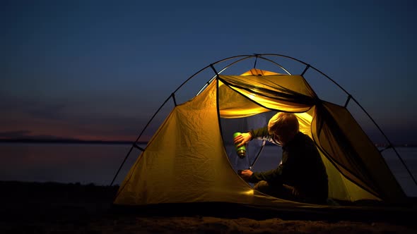 The Traveler is Sitting Comfortably in a Yellow Tent and Pouring a Hot Drink