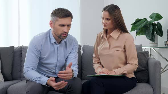 Sad Man Patient Talking About His Problem with Woman Psychologist Supporting Him
