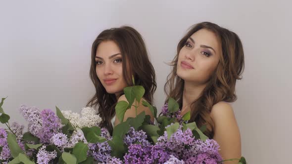 Studio Fashion Portrait Photo of Two Twins Women with a Bouquet of Spring Flowers