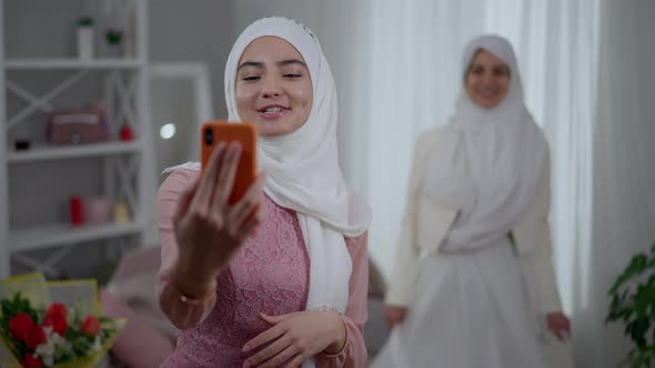 Modern Middle Eastern Bridesmaid Streaming Online Using Smartphone Talking and Smiling As Happy