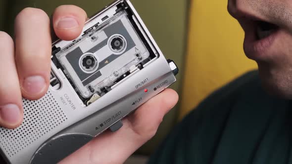 A Young Man Is Recording His Speech on a Portable Retro Cassette Recorder