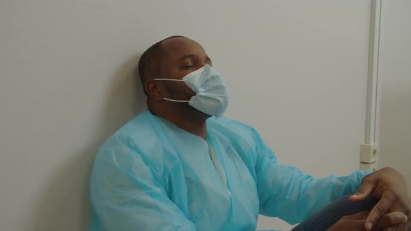 Portrait of Exhausted Black Male Surgeon with Eyes Closed Relaxing After Hard Surgery at Hospital