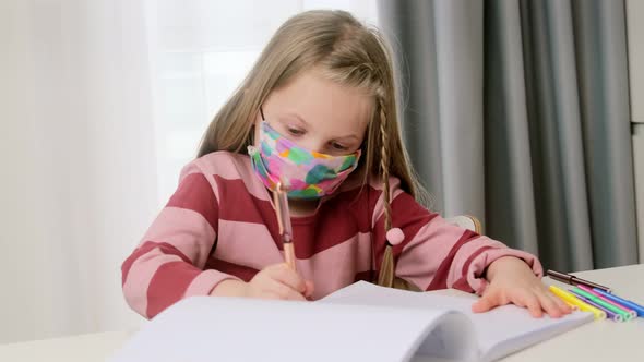 Little girl child wear face protective mask studying at school in classroom and doing homework