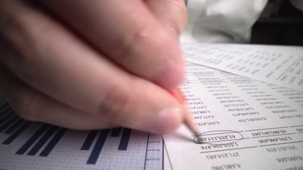 Accountant analyzing business marketing data on paper dashboard at office table.