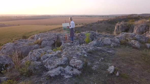 Girl artist paints a picture with oil paints. Aerial view