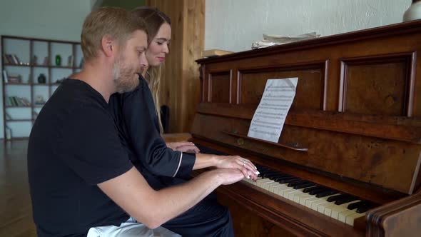 A Beautiful Married Couple Play the Piano Together, the Wife Guides Her Husband's Hands, They