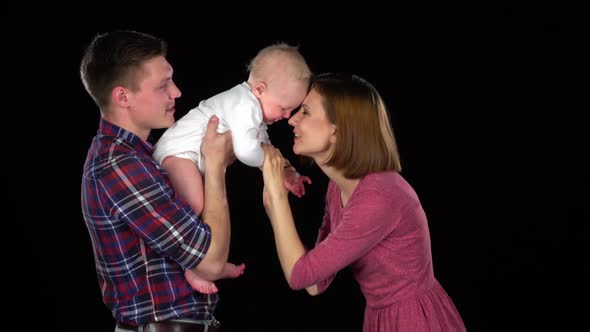 Mother, Father and Baby Laughing Together Playing. Black