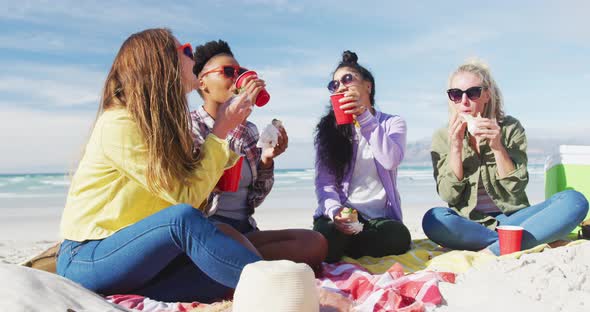 Happy group of diverse female friends having fun, having picnic at the beach