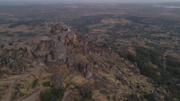 Aerial drone forward view over Monsanto hilltop castle ruins at sunset in Portugal