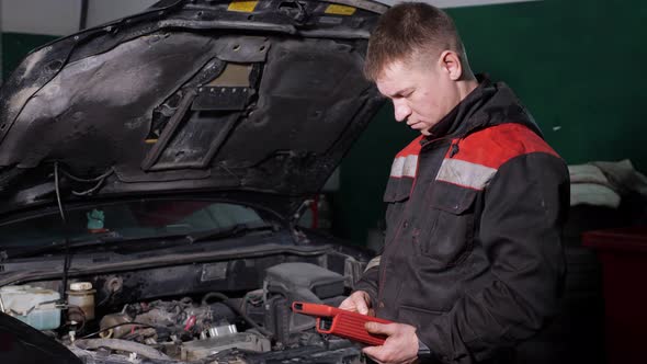 Worker Uses Digital Device to Check Automobile at Station