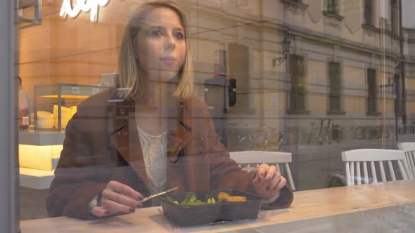 Young woman eating a salad in cafe in the city
