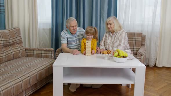 Senior Couple Grandparents with Child Kid Granddaughter Playing Game with Wooden Blocks at Home