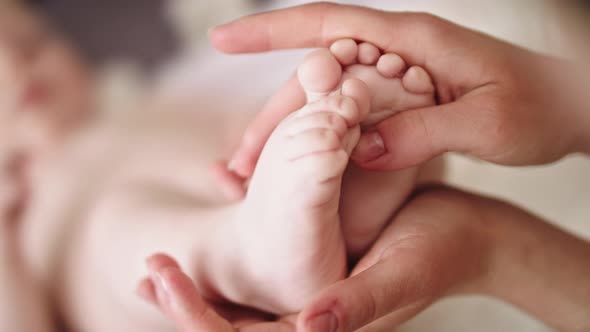 Mother Massaging and Tickling Small Baby Feet. Close Up Slow Motion Shot