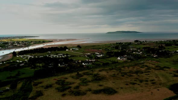 Aerial view over Irish coastal village and Lambay Island at sunset.