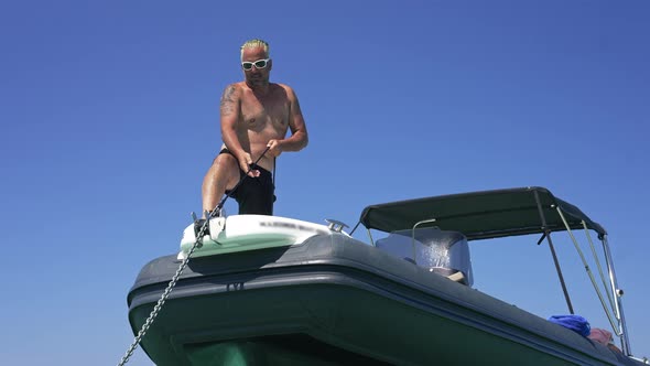 Bottom Angle View of Boat Captain Pulling Anchor Chain in Slow Motion at Background of Blue Summer