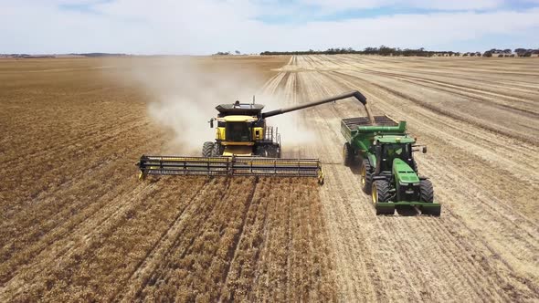 A combine harvests corn and load it directly on to a tractor trailer at the same time - aerial view