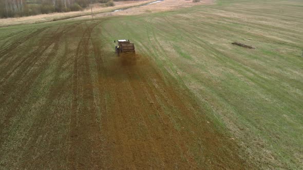 Farmer in a Tractor Throws Manure on the Field