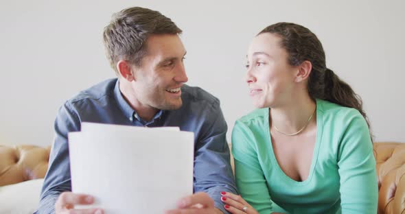 A young caucasian couple talking and paying their bills using a laptop