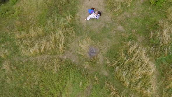 Aerial View at Three Girlfriends Wearing Long Summer Fashion Dress Walking Near Lake or River