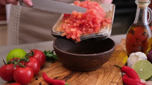 Woman Pours Chopped Peeled Tomato From Chopping Board to Wooden Bowl