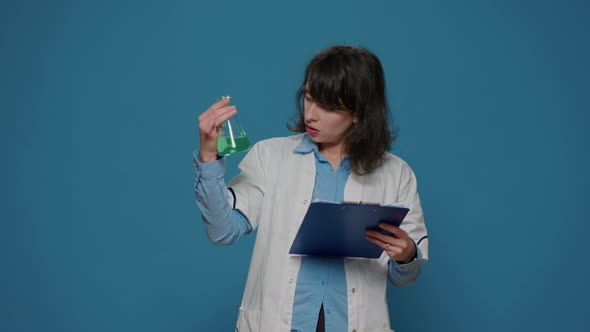 Female Scientist Analyzing Liquid in Beaker and Chemistry Files